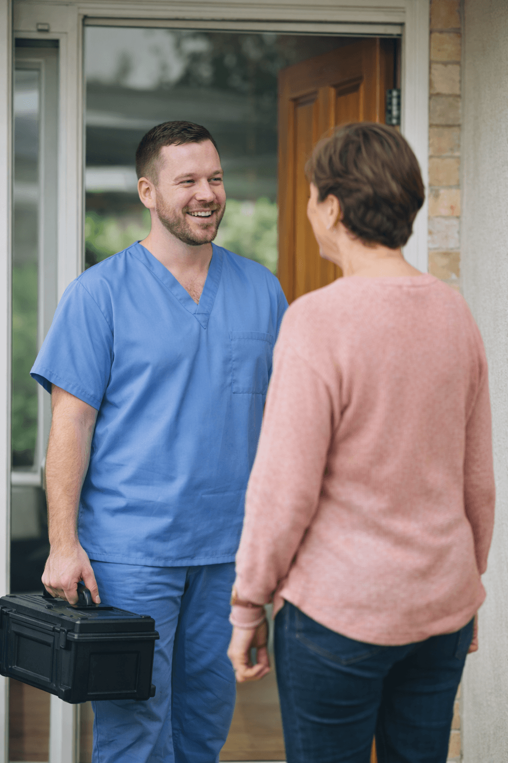 Podiatrist arriving for a home visit and greeting a patient