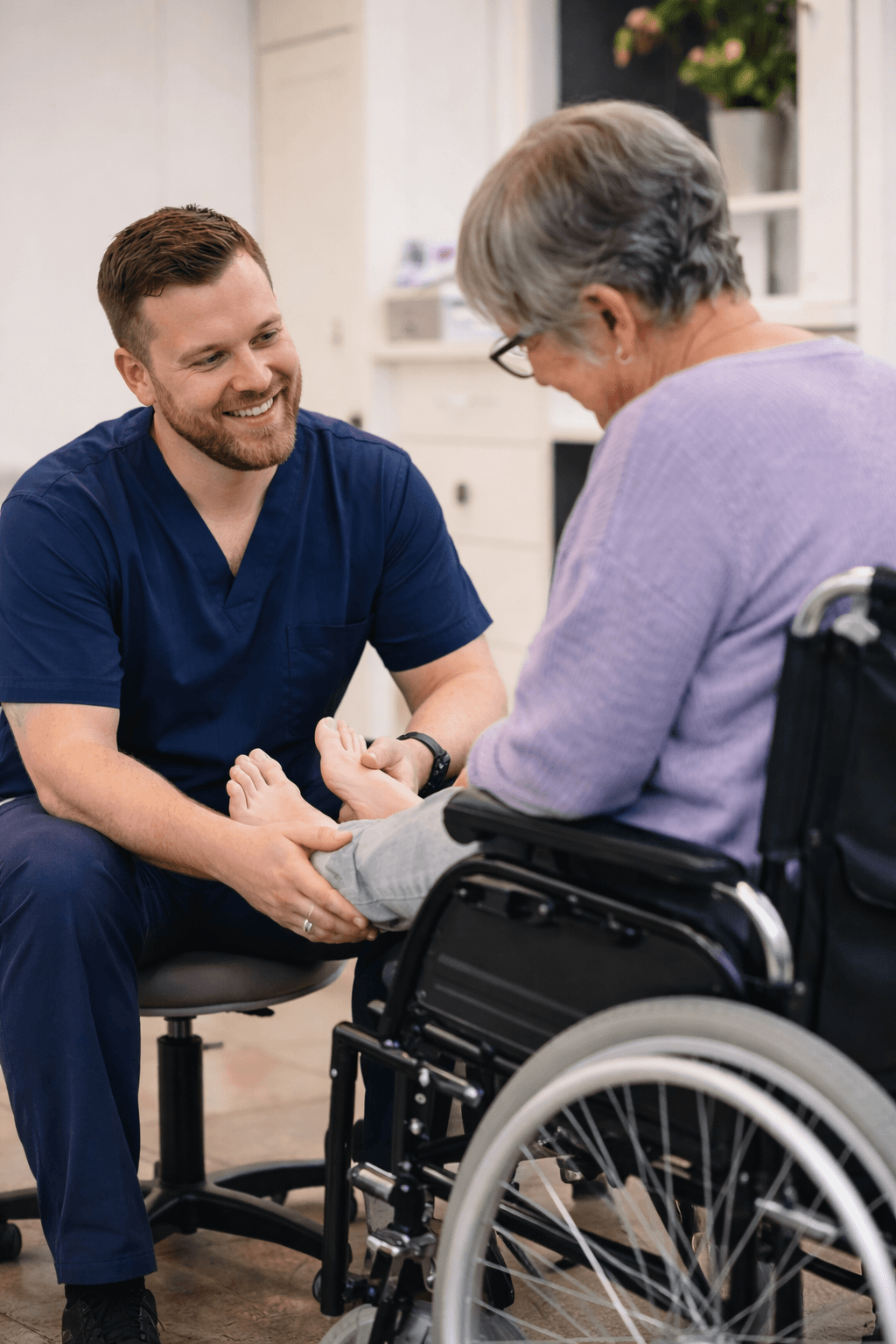 Podiatrist treating a client using a wheelchair during an NDIS visit
